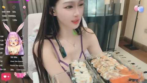 Media: A video of an Asian woman with long purple hair, wearing a purple bralette, eating sushi while a live stream is displayed on a smartphone.