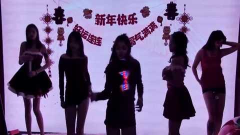 Media: Video of five young Asian women in dark, form-fitting outfits, standing in a line, holding hands, against a backdrop with Chinese lanterns and banners.