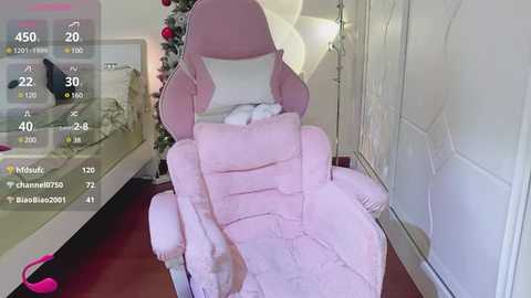 Media: Video of a pink, plush gaming chair with a child in a white blanket, sitting in a modern room with a Christmas tree and white doors.