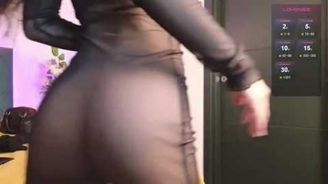 Media: A video of a person's lower back and buttocks in a tight, black, sheer bodysuit, with a digital screen displaying game stats in the background.