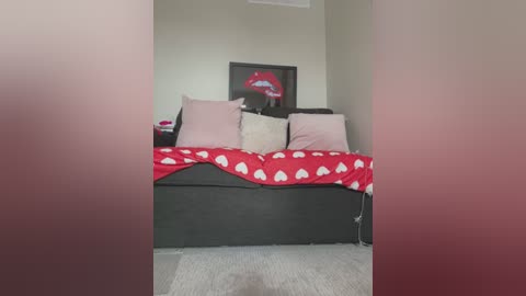 Media: A video of a neatly made bed with red heart-patterned sheets, pink pillows, and a framed red lips print on the beige wall.