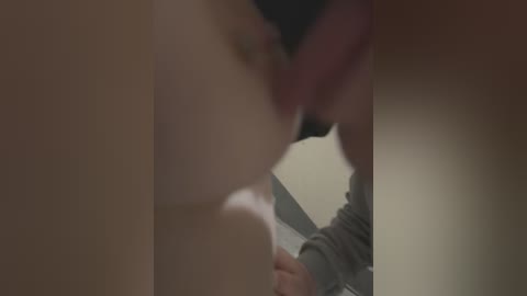 Media: A blurred video depicts a close-up of two people kissing passionately, with visible tongues. The background is out of focus, featuring a beige wall and a person's arm in a gray sweater.