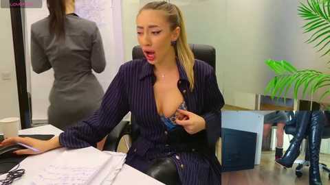 Media: Video of a blonde woman in a blue pinstriped dress exposing her bra, sitting at a desk in an office.