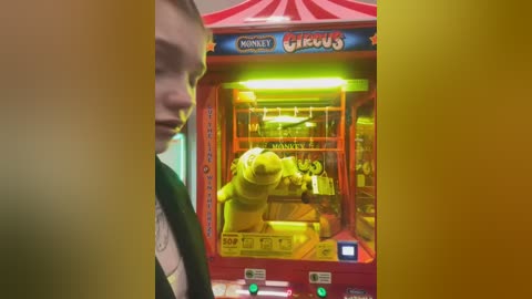 Media: Video of a child's face partially obscured by a yellow overlay. In the background, a vibrant, yellow LEGO toy vending machine with a LEGO Minifigure prominently displayed inside.