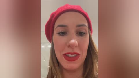 Media: Video of a woman with fair skin, wearing a red beret, red lipstick, and subtle makeup, set against a blurred background.