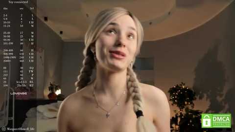 Media: Video of a blonde woman with braided hair and bare shoulders, smiling in a dimly lit, modern room with a TV showing a \"DMCA Takedown Notice\" screen.