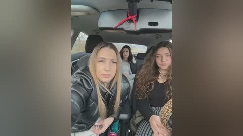 Media: Video of three young women in a car: one blonde in a black jacket, one brunette with curly hair, and another with straight hair, all looking serious.