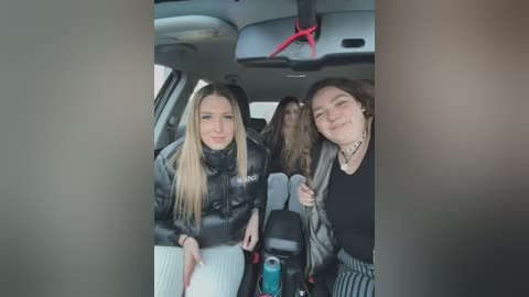 Media: Video of two young women, one blonde and one brunette, smiling, wearing black jackets, seated in a car with red seatbelt buckles.