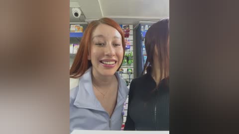 Media: Video of a cheerful redhead woman in a blue shirt smiling at a customer in a grocery store.