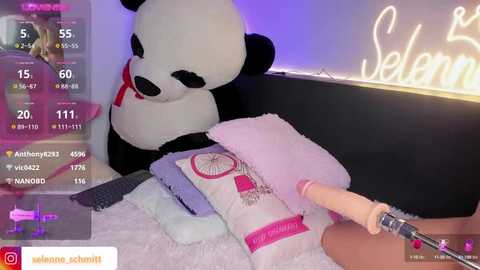 Media: A video shows a plush panda bear sitting on a bed, with a pink vibrator inserted into a pile of bedding. The room has a \"Welcome\" neon sign and a social media account watermark.