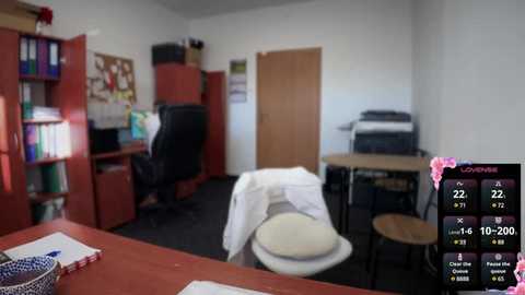 Media: Video of a dimly lit office with a messy desk, black chair, and a closed door. A TV screen in the bottom right shows a weather forecast.