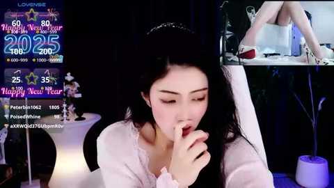 Media: A video of an East Asian woman with long black hair, wearing a white dress, shushing a man in a dimly lit room. Text overlays show dates and social media handles.