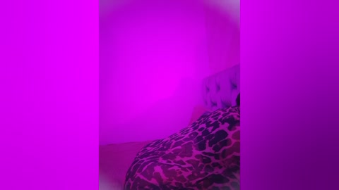 Media: Video: A person with short, dark hair, lying on a leopard-print blanket, partially obscured by a vibrant purple light.