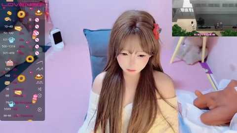 Media: Video of a young Asian woman with long, brown hair, wearing a yellow off-shoulder sweater, sitting on a bed in a pastel pink room. Superimposed on the image are smartphone icons and a video feed of a man's hand touching her shoulder.