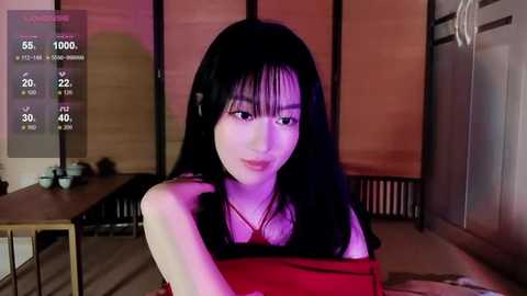 Media: Video of an Asian woman with long black hair and fair skin, wearing a red top, smiling. Background shows a wooden sliding door and a table.