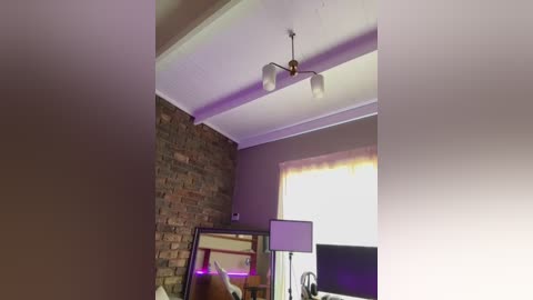 Media: Video of a modern, minimalist bedroom with a wooden-framed bed, a stone wall, a ceiling fan, and a large window with sheer curtains, illuminated by soft purple lighting.