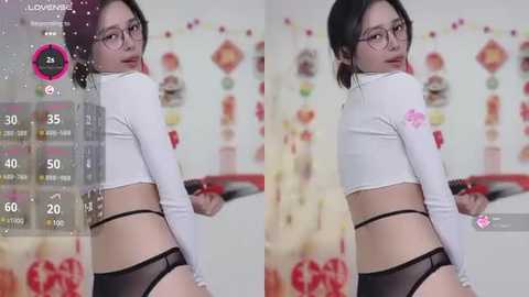 Media: A video of an East Asian woman with glasses, wearing a white crop top and black panties, standing in a colorful, softly lit room.