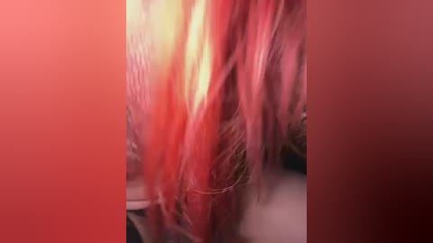 Media: A close-up video of vibrant, red-pink hair strands with a smooth texture, partially obscured by a red background. The focus is on the hair's silky sheen and soft, wavy texture.