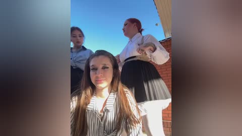 Media: Video of three young women in formal attire, standing on a rooftop, with one woman in the foreground facing the camera.