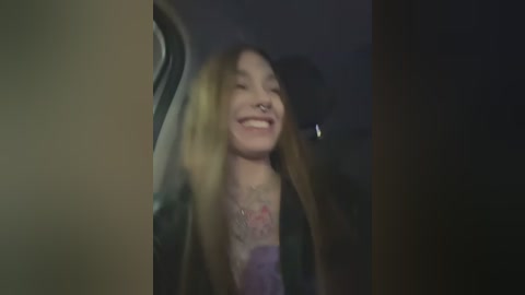 Media: A blurry video of a smiling young woman with long blonde hair, wearing a black jacket and purple top, captured from the car's window.