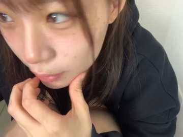 Media: A close-up video of an Asian woman with fair skin and straight brown hair, wearing a black jacket, touching her neck with a thoughtful expression. The background is plain white.