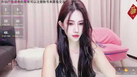 Media: A video of an East Asian woman with long black hair, fair skin, and makeup, sitting in a modern living room with beige walls, pink and gray furniture, and a digital temperature display.