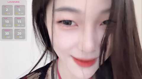 Media: Video of a young Asian woman with long black hair, fair skin, and red lipstick, smiling with visible tear streaks on her cheeks. Calendar grid in the background shows February 15th.