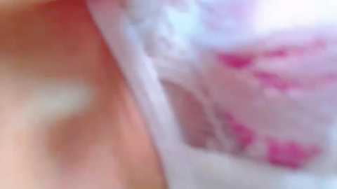 Media: A blurred video of a close-up scene featuring a woman's bare, light-skinned torso with visible breasts and pink nipples. The background is indistinct, with soft, pastel colors and an overall soft focus.