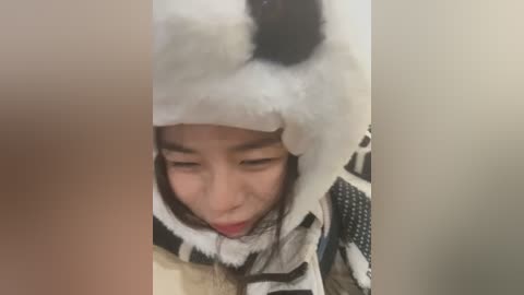 Media: A video of a young Asian girl in a panda costume, with a fluffy headpiece, smiling and making a silly face. The background is blurred, focusing on the girl's playful expression.