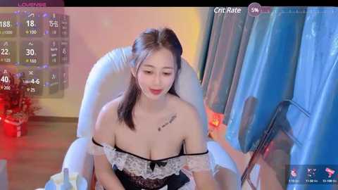 Media: A video of a young East Asian woman with fair skin and medium-length dark hair, wearing a revealing black and white lace dress with off-shoulder straps, sitting in a plush white chair.