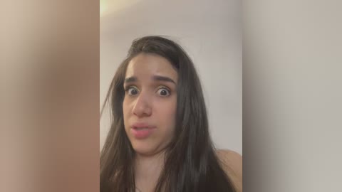 Media: Video of a young woman with long, dark hair, wearing a black top, looking surprised and making a funny face.