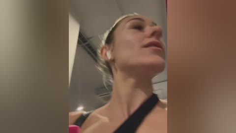 Media: A video of a Caucasian woman with light skin and blonde hair, wearing a black sports bra, taken from a low angle, showing her chest.