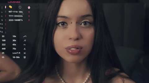 Media: A close-up video of a young woman with long, straight black hair, light skin, and full lips, wearing a black top, against a dark background. A phone screen with call logs and contact details is visible in the lower left corner.