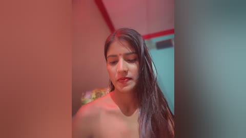 Media: A video of a young South Asian woman with long, wet hair, wearing a red bindi, standing in a dimly lit room with red and blue lighting.