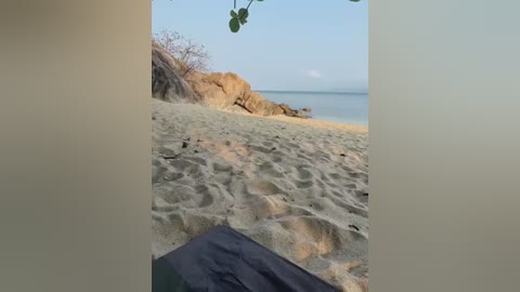 Media: A video captures a serene beach scene with sandy footsteps leading to a calm ocean, rocky shore, and distant mountains.