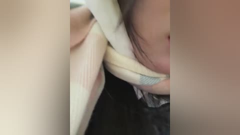 Media: Video of a close-up of a woman's face with light skin, resting her head on a light-colored pillow, her dark hair partially covering her face.