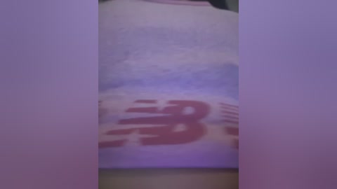 Media: A blurry video of a white shirt with a partially visible red logo on the left side, likely a restaurant name. The background is out of focus, suggesting a casual indoor setting.