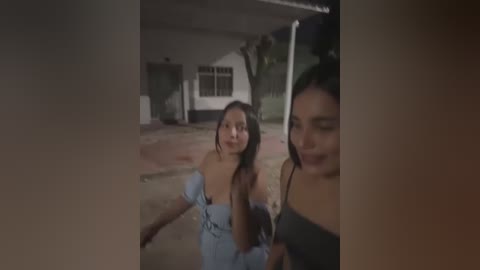 Media: Video of two young women walking outdoors at night; one in a light blue off-shoulder dress, the other in a black top, both smiling.