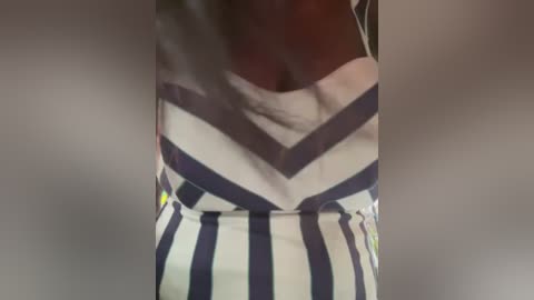 Media: Video of a person wearing a white dress with navy blue chevron patterns, blurred background, focusing on the waist and chest area.