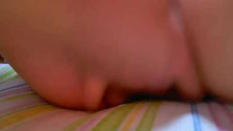 Media: A blurry video of a person's buttocks and thigh on a striped bedsheet. The skin appears fair, with a slight reddish hue. The background shows a mix of green, yellow, and white stripes.