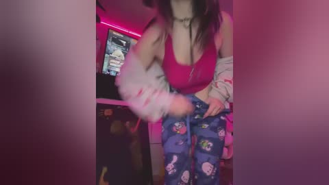 Media: A video of a young woman in a dimly lit room, wearing a pink crop top, blue pajama pants with cartoon characters, and a white jacket, holding a cigarette, with a neon pink light accenting the background.