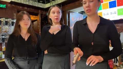 Media: Video of three women in black blouses and pinstriped skirts, one with a wooden spoon, in a cozy, warmly lit bar.