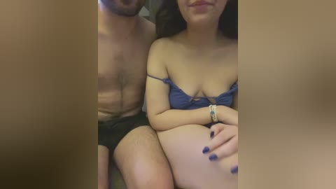 Media: Video of a light-skinned woman with dark hair, wearing a blue lace bra, sitting on a man's lap, both partially out of focus.