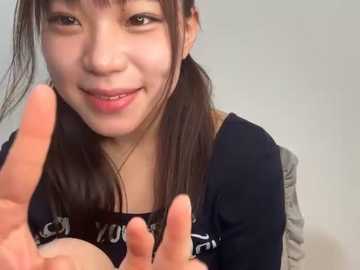 Media: Video of a young Asian woman with long black hair, smiling, wearing a black shirt, making a peace sign with her fingers.