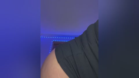 Media: A video of a person's lower body, viewed from the side. The subject is wearing black shorts, and the background features blue LED lights.