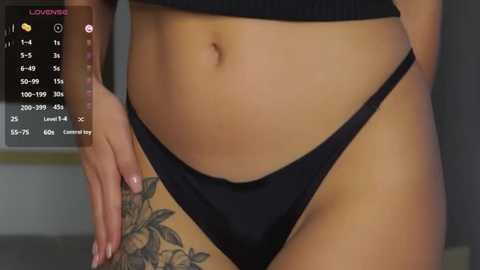 Media: Video of a woman's midsection in black underwear, showcasing a detailed floral tattoo on her left thigh.