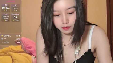 Media: A video of a young Asian woman with long black hair, wearing a black top, looking down, surrounded by virtual social media icons.