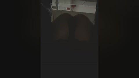 Media: A dimly lit video captures a person's legs in black pants and white socks, with a red object visible in the background, suggesting a bathroom setting.