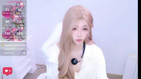 Media: Video of a young, fair-skinned, long-haired Asian woman with a pink headband, wearing a white coat and black stethoscope, seated on a white chair. Background is a plain white room.