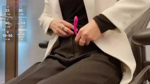 Media: A video of a person, wearing a white coat and black pants, using a pink vibrator in a medical examination chair, with a digital display showing temperature and other vital signs.